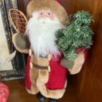 A santa clause doll holding a tennis racket.