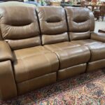 A brown leather couch sitting in front of a rug.