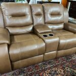 A brown leather couch with two cup holders.