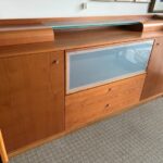 A wooden entertainment center with glass doors and drawers.