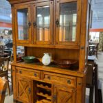 A wooden cabinet with glass doors and drawers.