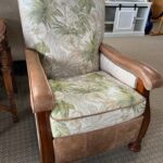 A chair with floral fabric and leather arms.