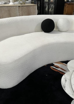Curved white bouclé sofa with round pillows