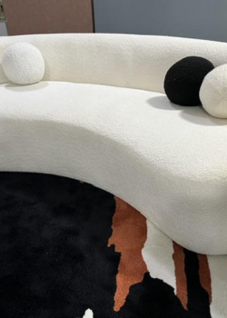 Curved boucle sofa with round pillows on rug