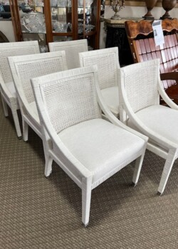 Six white upholstered chairs with cane backs.