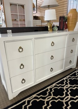 White dresser with brass handles and decor.